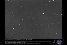 scattered white specks against grey background, one speck identified with arrow