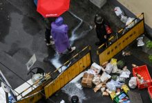 Des livreurs devant une barrière fermant l'accès à un quartier confiné de Shanghai, le 23 avril 2022 en Chine (AFP - Hector RETAMAL)