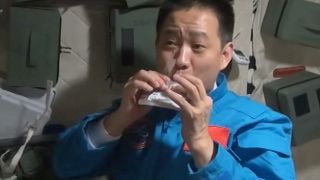 A still image of a Chinese astronaut eating in space.